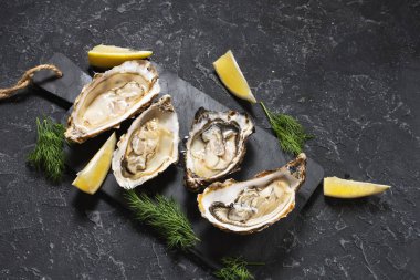 Karanlık taş doku zemin üzerine limon ile açılan istiridye