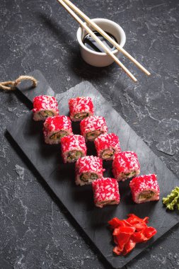 Suşi dürümleri siyah taş üzerine servis edilir. Siyah arka planda..