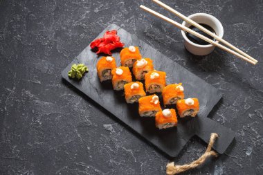Suşi dürümleri siyah taş üzerine servis edilir. Siyah arka planda..
