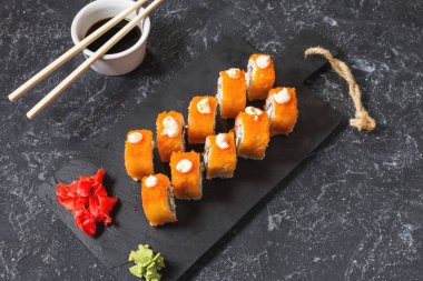 Suşi dürümleri siyah taş üzerine servis edilir. Siyah arka planda..