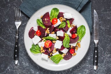 Beyaz, kırmızı pancar, kiraz domates ve ceviz taş zemin üzerine salata yemek. Üstten görünüm