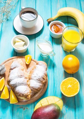 Kahve, portakal suyu, kruvasan ve meyve mavi ahşap arka plan üzerinde sunulan kahvaltı