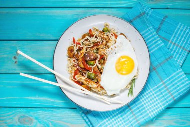 Udon kizartma noodles ile mavi ahşap arka plan üzerinde tavuk. Üstten görünüm