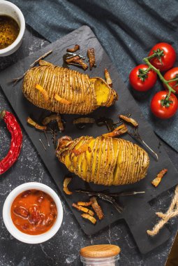 Karanlık taş zemin üzerine kavrulmuş hasselback patates. Üstten görünüm