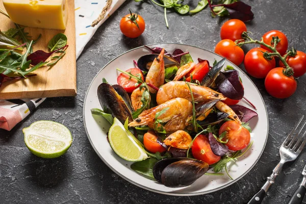 Taze deniz ürünleri salatası, midye, karides, taze sebze ve otlar siyah taş zemin üzerine