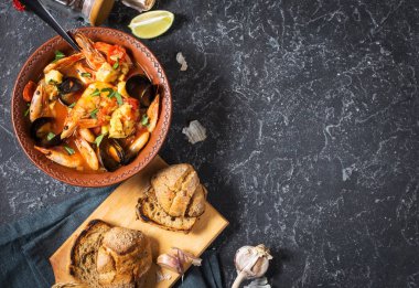 Fransızca balık çorbası Bouillabaisse deniz ürünleri, somon fileto, karides, midye siyah taş zemin üzerine. Lezzetli yemek. Üstten Görünüm ve kopya alanı