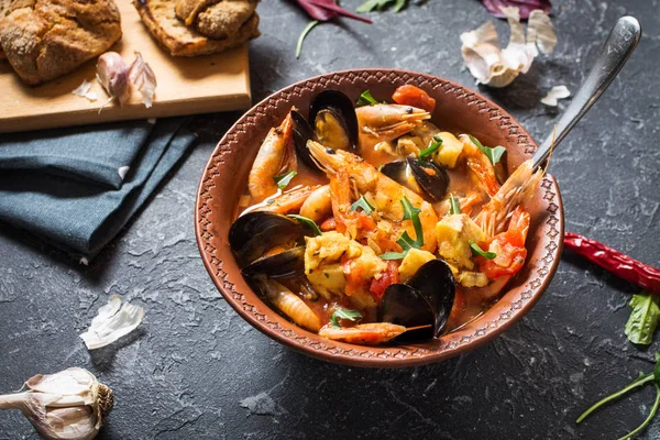 Fransızca balık çorbası Bouillabaisse deniz ürünleri, somon fileto, karides, midye siyah taş zemin üzerine. Lezzetli akşam yemeği