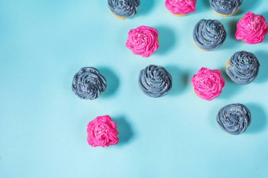 Lezzetli pembe ve gri cupcakes mavi zemin üzerine üst üste. Üstten Görünüm