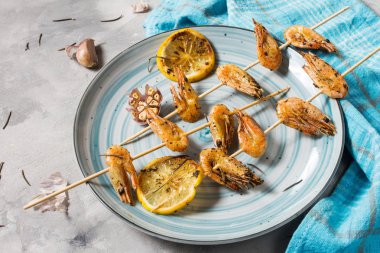 Izgara karides şiş şifreli otlar, sarımsak ve limon beton zemin üzerine. Deniz ürünleri