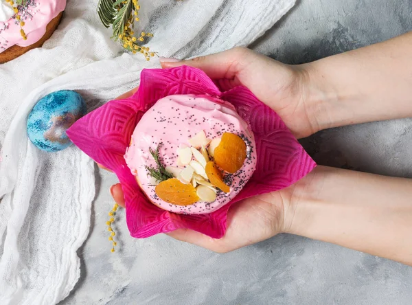 Female hands hold Easter orthodox sweet bread, kulich on concrete background. — Stock Photo, Image