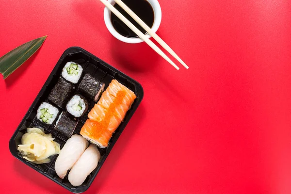Vários tipos de rolos de sushi servidos no fundo vermelho — Fotografia de Stock