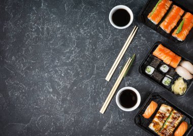Siyah taş arka planda servis edilen çeşitli suşi çeşitleri.
