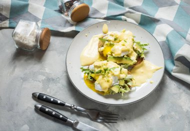 Beton arka plan üzerinde avokado ile Yumurta Benedict.