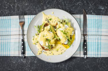 Yumurta Benedict salata ve avokado taş arka plan üzerinde.