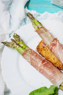 Taze Genç Kuşkonmaz Prosciutto Et sarılmış mavi ahşap masada.