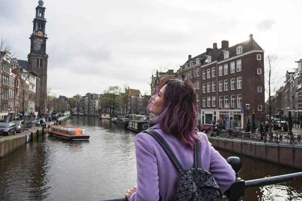 Mont ve sırt çantası nda Amsterdam şehrinin tadını çıkaran kız. Amsterdam kanalında yan yana bakan genç kadın