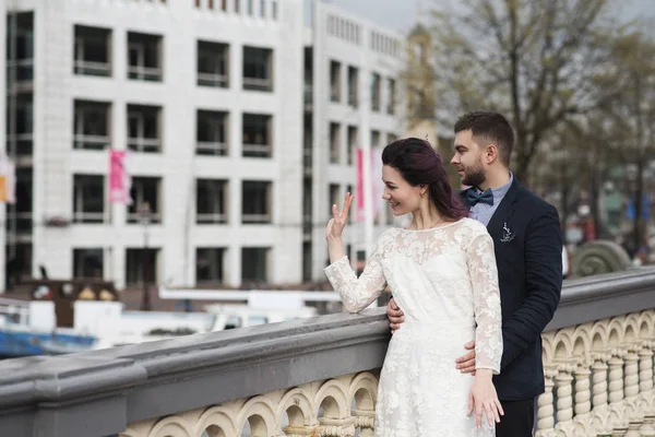 Wedding photo shooting. Bride and bridegroom walking in Amsterdam. Stand on bridge and hug.