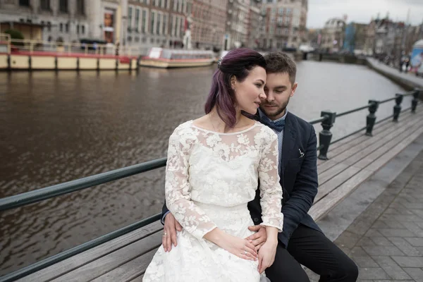 Wedding photo shooting. Bride and bridegroom walking in Amsterdam. Stand on bridge and hug.