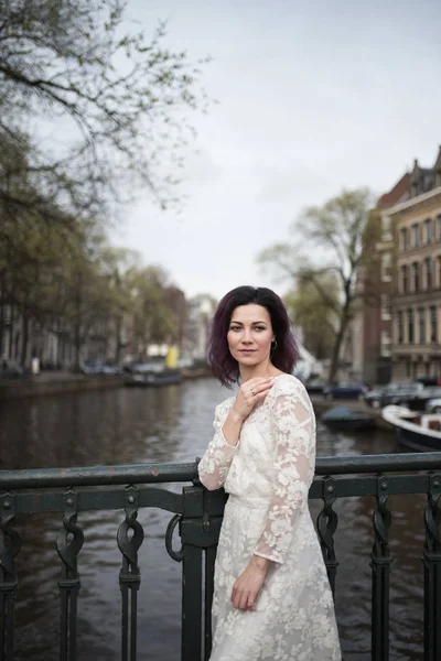 Wedding photo shooting. Bride walking in Amsterdam. Stand on bridge and hug.