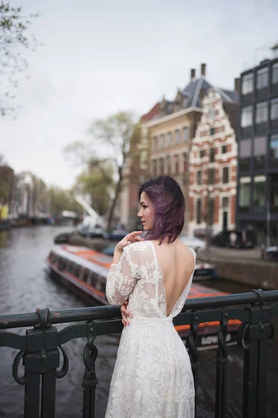 Wedding photo shooting. Bride walking in Amsterdam. Stand on bridge and hug.