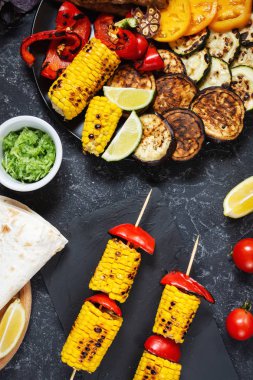 Koyu taş arka planda çeşitli lezzetli ızgara sebzeler ve et. Yaz yemekleri Barbekü.