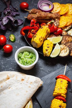 Koyu taş arka planda çeşitli lezzetli ızgara sebzeler ve et. Yaz yemekleri