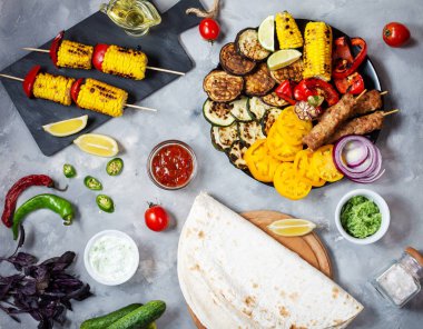 Beton bir arka plan üzerinde çeşitli lezzetli ızgara sebze ve et. Yaz yemeği barbekü.