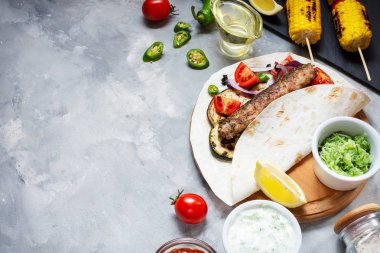 Beton bir arka plan üzerinde çeşitli lezzetli ızgara sebze ve döner kebap. Yaz yemeği barbekü.