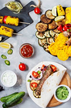 Beton bir arka plan üzerinde çeşitli lezzetli ızgara sebze ve döner kebap. Yaz yemeği barbekü.
