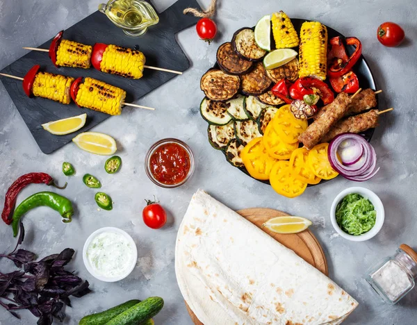 Beton bir arka plan üzerinde çeşitli lezzetli ızgara sebze ve et. Yaz yemeği barbekü.