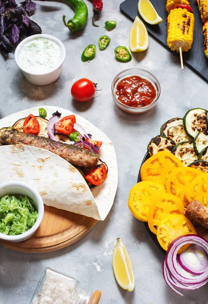Beton bir arka plan üzerinde çeşitli lezzetli ızgara sebze ve döner kebap. Yaz yemekleri.