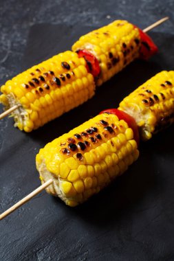 Çubuklar üzerinde Izgara tatlı mısır, siyah taş masa