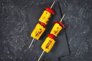 Çubuklar üzerinde Izgara tatlı mısır, siyah taş dokulu masa