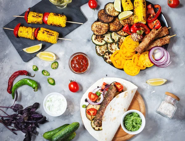 Beton bir arka plan üzerinde çeşitli lezzetli ızgara sebze ve döner kebap. Yaz yemeği barbekü.
