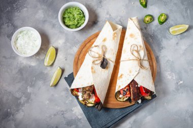 Beton arka plan üzerinde ızgara sebze ve et ile sarma sandviç.