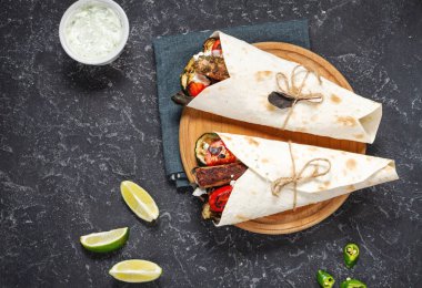 Siyah taş arka plan üzerinde ızgara sebze ve et ile sarma sandviç