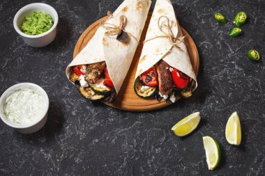 Taş arka plan üzerinde ızgara sebze ve et ile sarma sandviç.