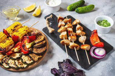 Beton bir arka plan üzerinde şişler üzerinde çeşitli lezzetli ızgara sebze ve tavuk kebap. Yaz barbekü.