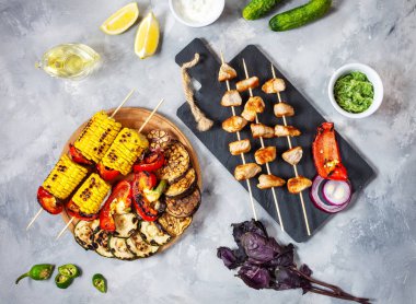 Beton bir arka plan üzerinde şişler üzerinde çeşitli lezzetli ızgara sebze ve tavuk kebap. Yaz yemeği barbekü.