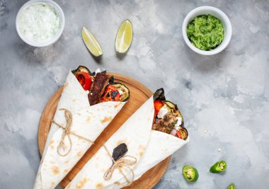 Beton arka plan üzerinde ızgara sebze ve et ile sarma sandviç.