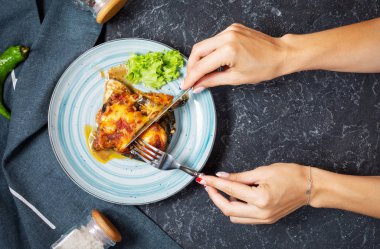 Dişi eller bıçak ve çatal tutar. Bir taş masada peynir ile fırında patlıcan. Parmigiana melanzane.