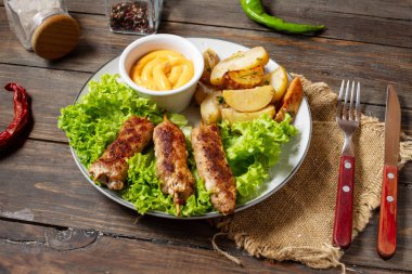 Izgara şiş kebap ahşap arka plan üzerinde kızarmış patates ve sos ile servis