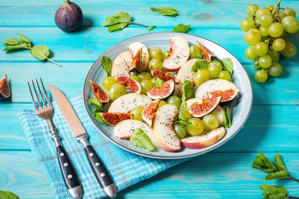 Vers fruit en bessen salade met druiven, vijg en perzik op blauwe houten achtergrond. — Stockfoto