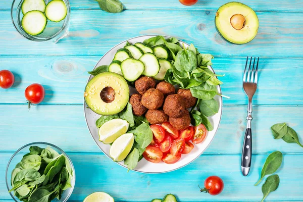 Salată cu avocado, falafel, castravete, roșii cherry și spanac pe fundal din lemn albastru . — Fotografie, imagine de stoc
