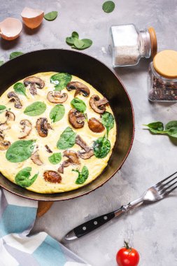 Beton arka plan üzerinde tavada mantar ve ıspanak ile Omlet.