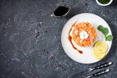 Lezzetli avokado ve siyah taş arka planda tuzlu somon tartarı.