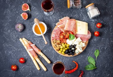 İtalyan antipasto, jambon, peynir, zeytin ve siyah taş arka planda Grissini ekmeği. Üst görünüm