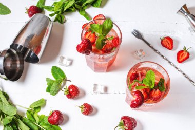 Çilekli mojito ve beyaz ahşap arka planda malzemeler..