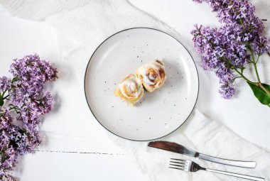 Tarçınlı rulo ya da beyaz ahşap zemin üzerinde beyaz krema jöleli tarçın. Geleneksel ev yapımı tatlı çörekler. Üst görünüm