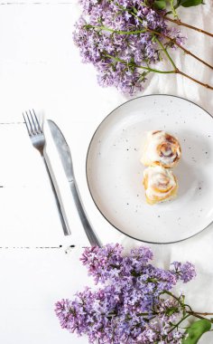 Tarçınlı rulo ya da beyaz ahşap zemin üzerinde beyaz krema jöleli tarçın. Geleneksel ev yapımı tatlı çörekler. Üst görünüm